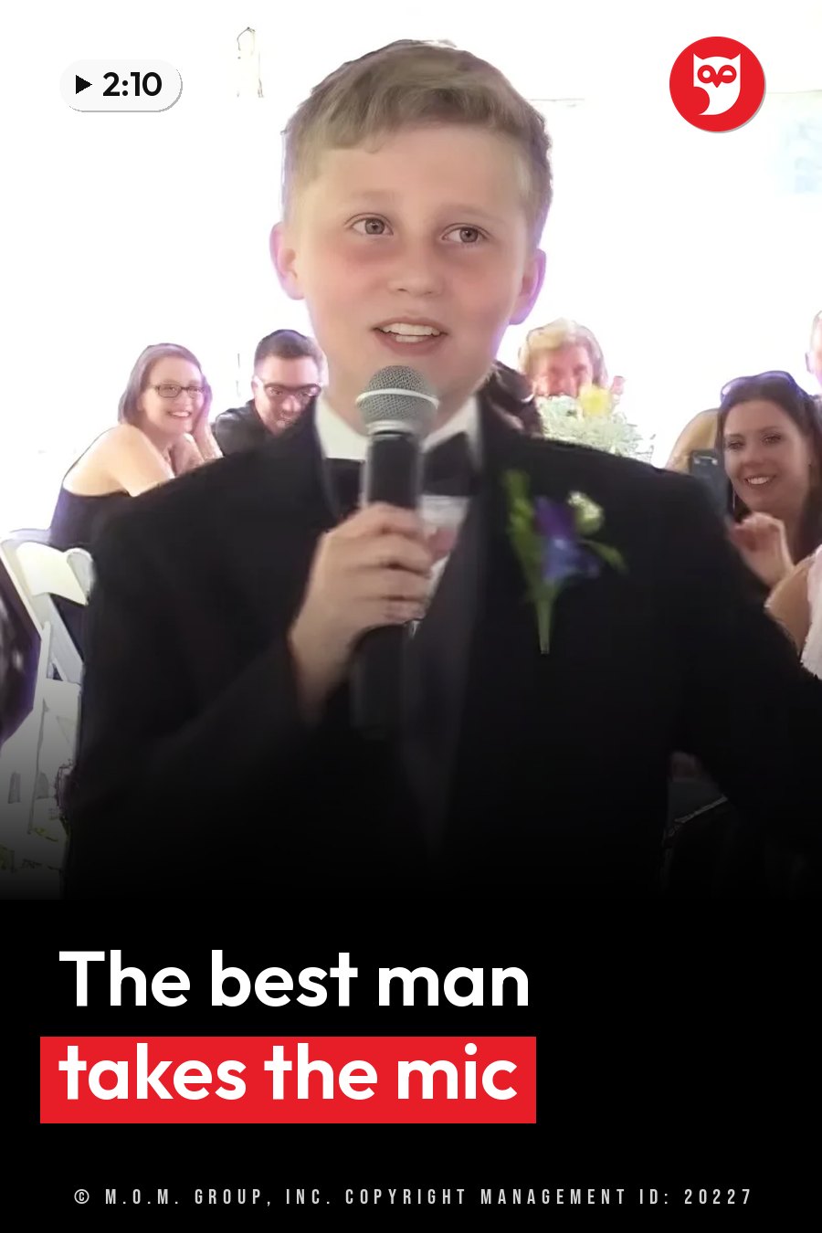 R.J., a young boy in a suit, holds a microphone and speaks, with seated guests behind him. A headline runs in white letters across the lower third.