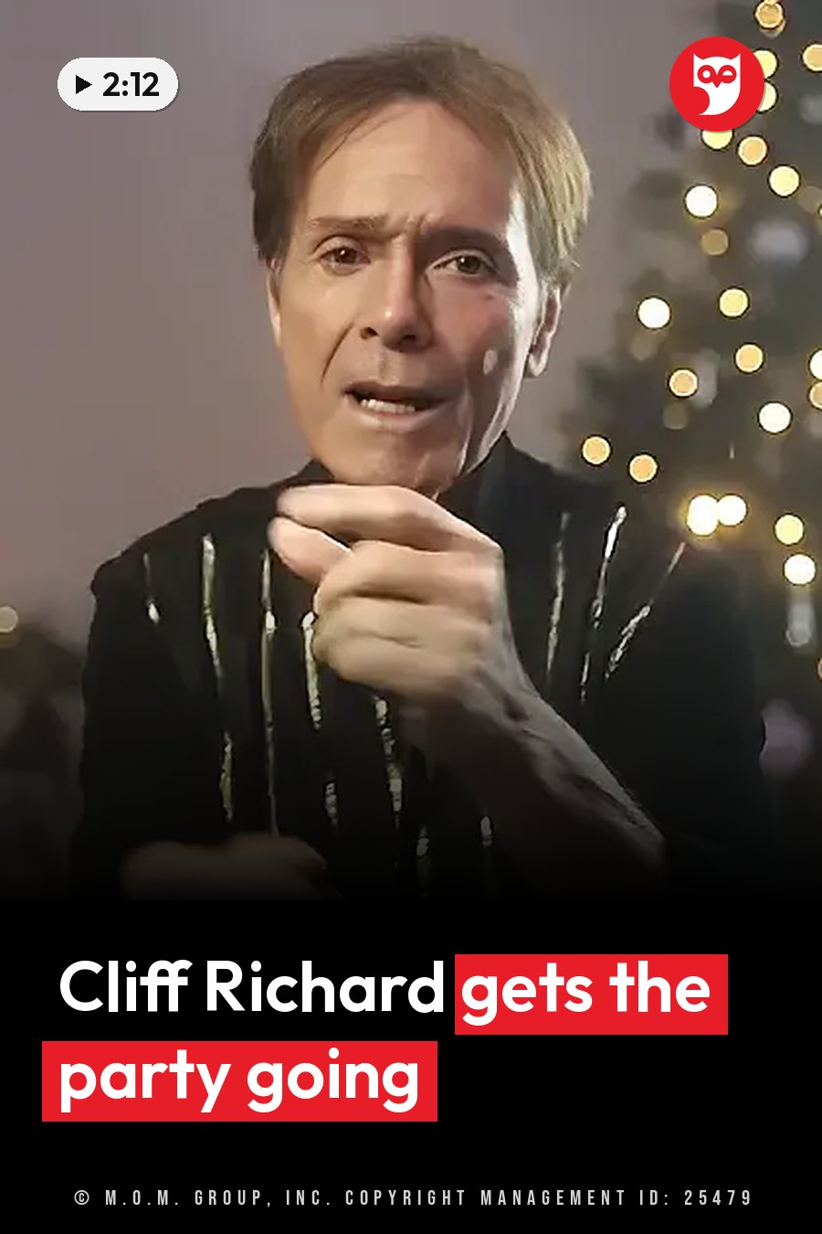 Cliff Richard in a dark, shiny jacket points forward with his right hand, with blurred lights behind him. A headline runs in white letters across the lower third.