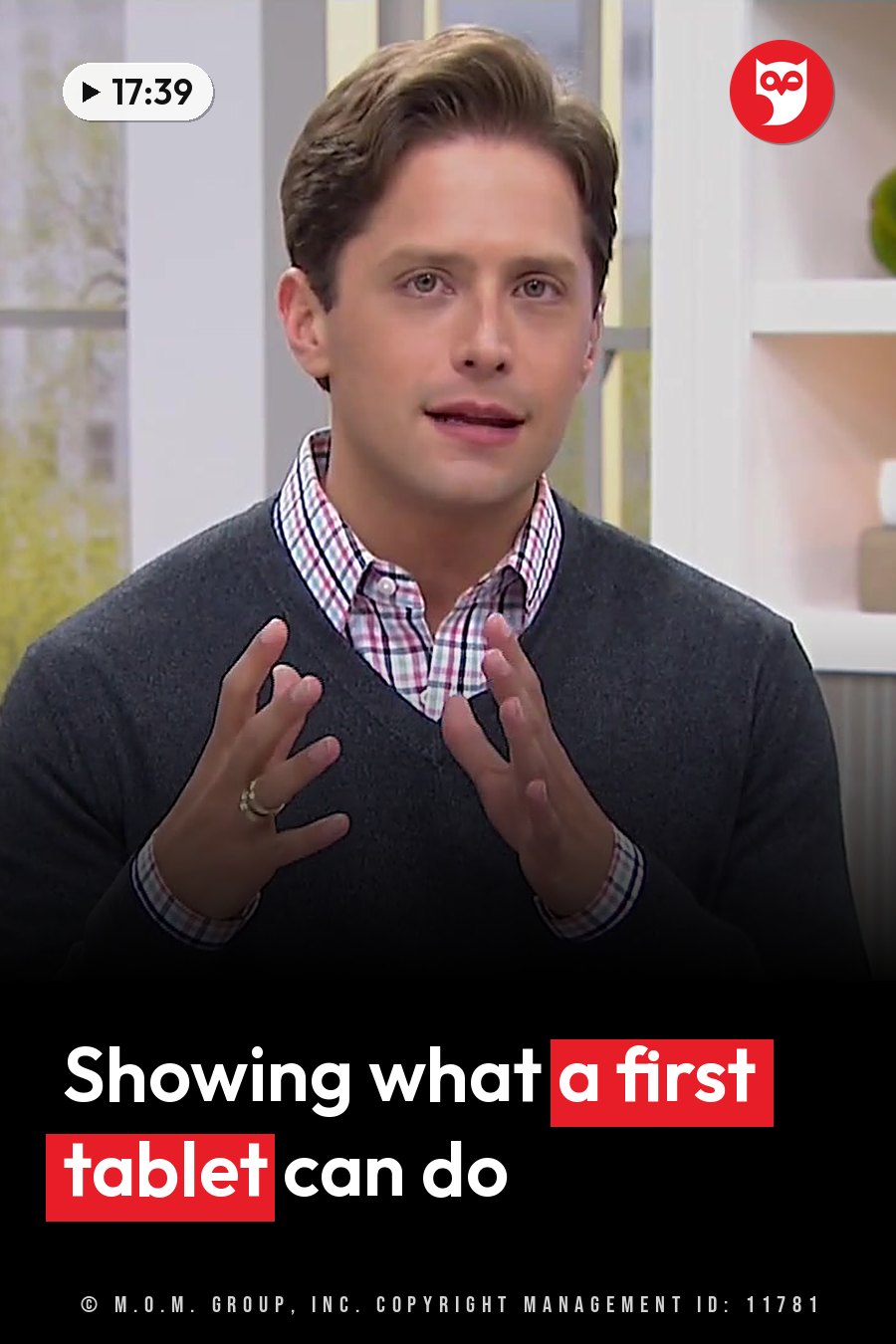 A man with brown hair in a gray sweater over a plaid shirt gestures while speaking indoors near shelves. A headline runs in white letters across the lower third.
