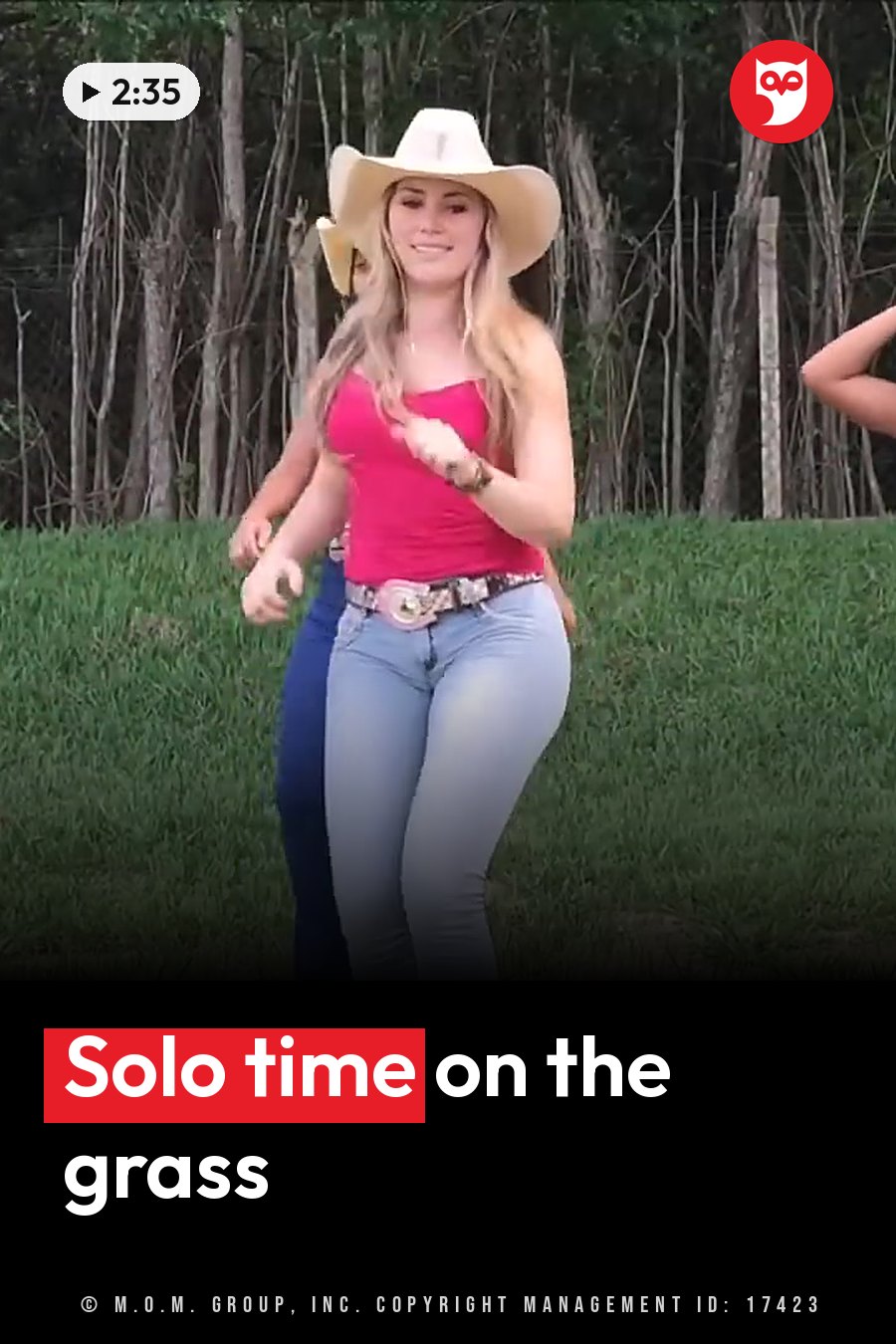 A woman in a cowboy hat, red top and jeans dances on grass near trees. A headline runs in white letters across the lower third.