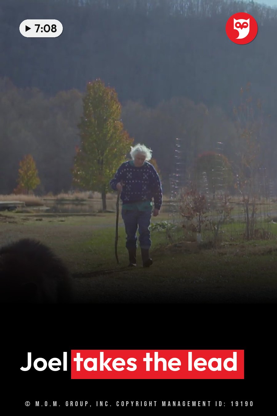 Joel Rosenthal, white-haired, walks through a grassy field with a cane, wearing a patterned sweater and boots. A headline runs in white letters across the lower third.