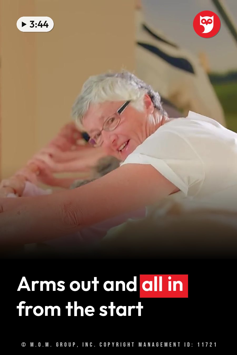 An older woman with glasses smiles and leans forward with her arms stretched out in front of her. A headline runs in white letters across the lower third.