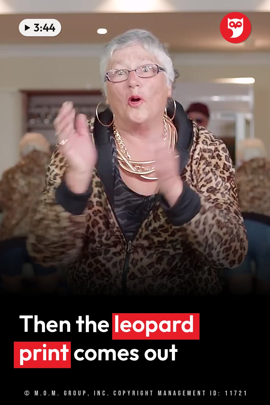 An older woman with glasses, a leopard-print jacket and gold jewelry claps her hands while looking ahead. A headline runs in white letters across the lower third.
