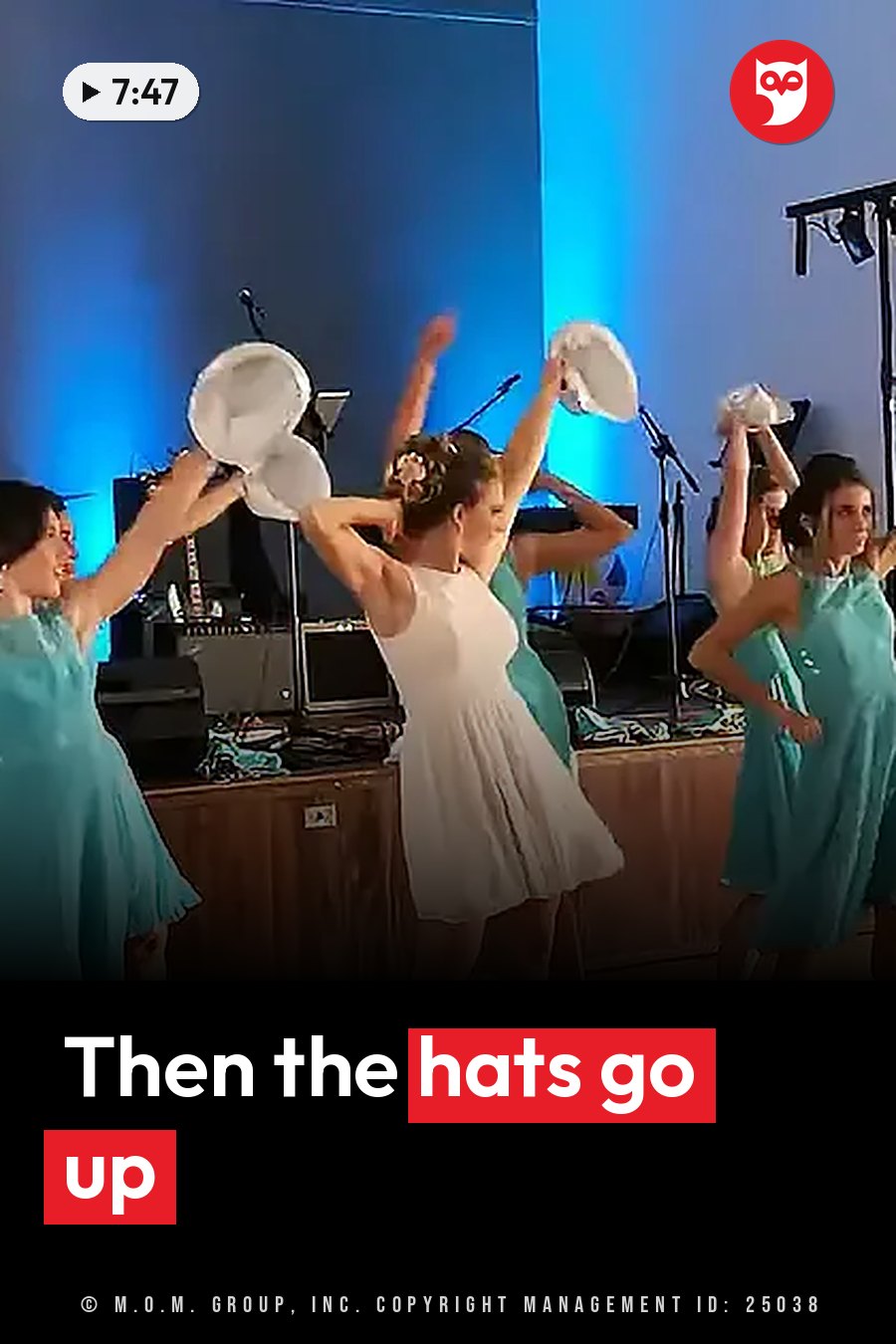 Women in dresses hold white hats above their heads while dancing on a stage with blue lighting and music gear behind them. A headline runs in white letters across the lower third.