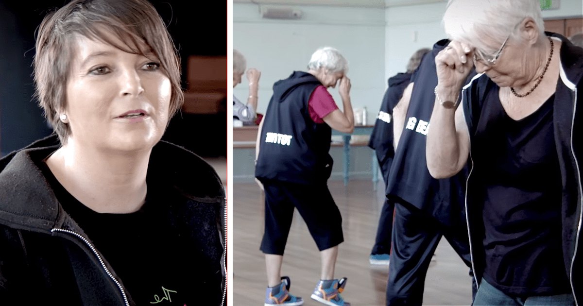 Middle-aged woman in a dance class with older adults and light-colored walls, daytime indoor setting.