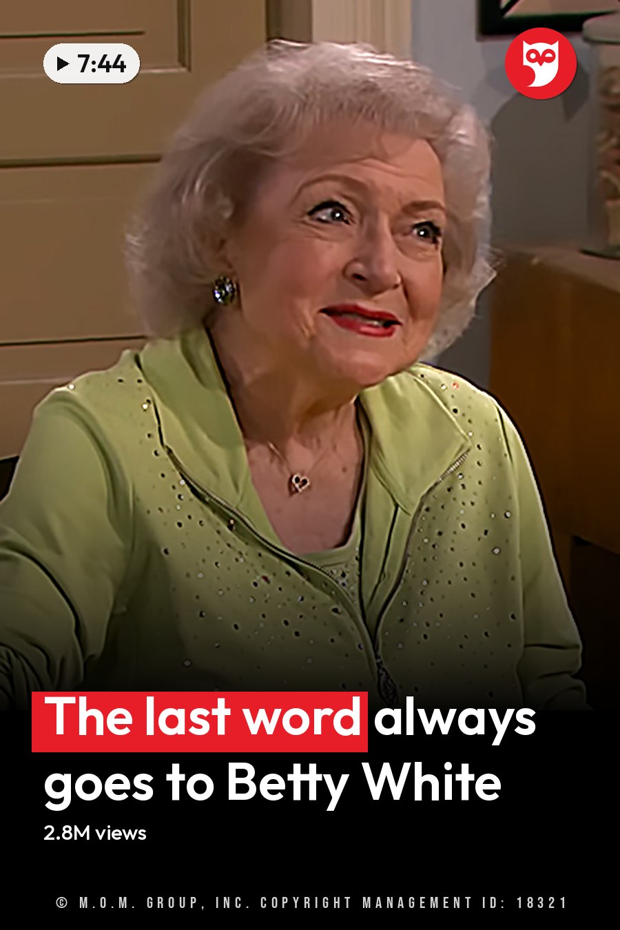 An older adult female wearing a light green zip-up cardigan with small sequins and a heart pendant necklace, sitting at a wooden table in a cozy kitchen setting with red placemat and various home decor items. The headline runs in white letters across the lower third.