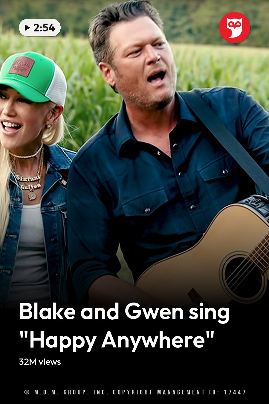 A musical duo in an outdoor rural setting with cornfields, late summer or early fall attire, soft morning or evening light. Both individuals wear bracelets and layered necklaces; one holds a light brown acoustic guitar. The headline runs in white letters across the lower third.