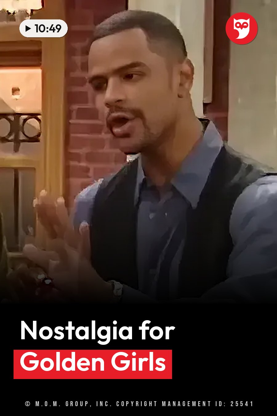A man with short hair and a goatee, in a vest over a shirt, gestures as he speaks indoors near a brick wall. A headline runs in white letters across the lower third.