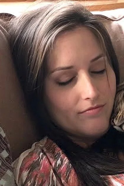 An adult female with a tabby cat in a cozy living room setting, bathed in natural light.