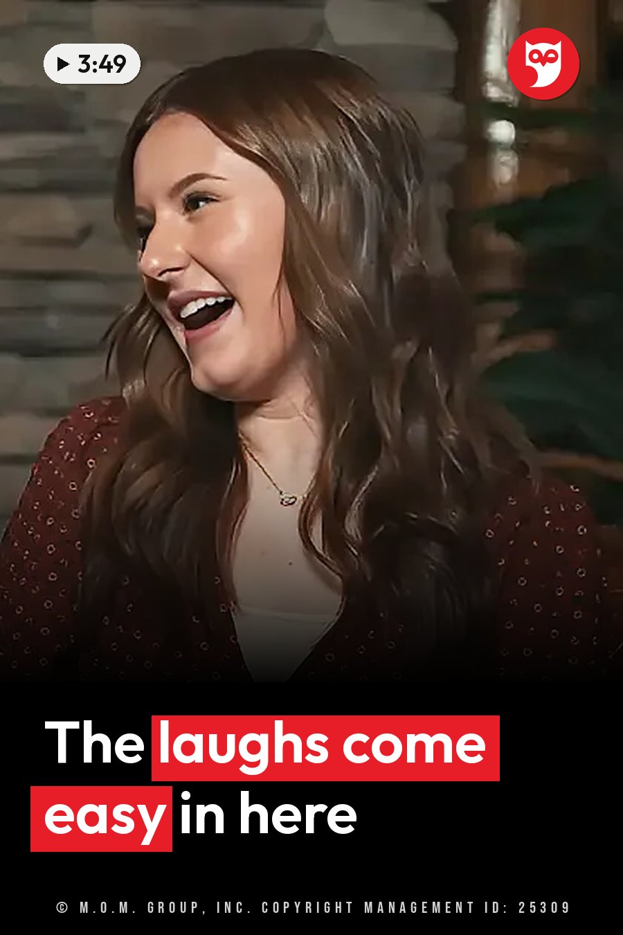 A woman with long brown hair laughs indoors, wearing a patterned red top and a necklace. A headline runs in white letters across the lower third.