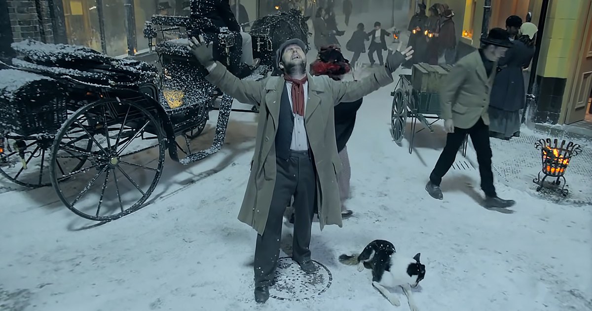 Adult Border Collie with black and white coat in a snowy urban town square during daylight hours, surrounded by horse-drawn carriages and people in winter attire.