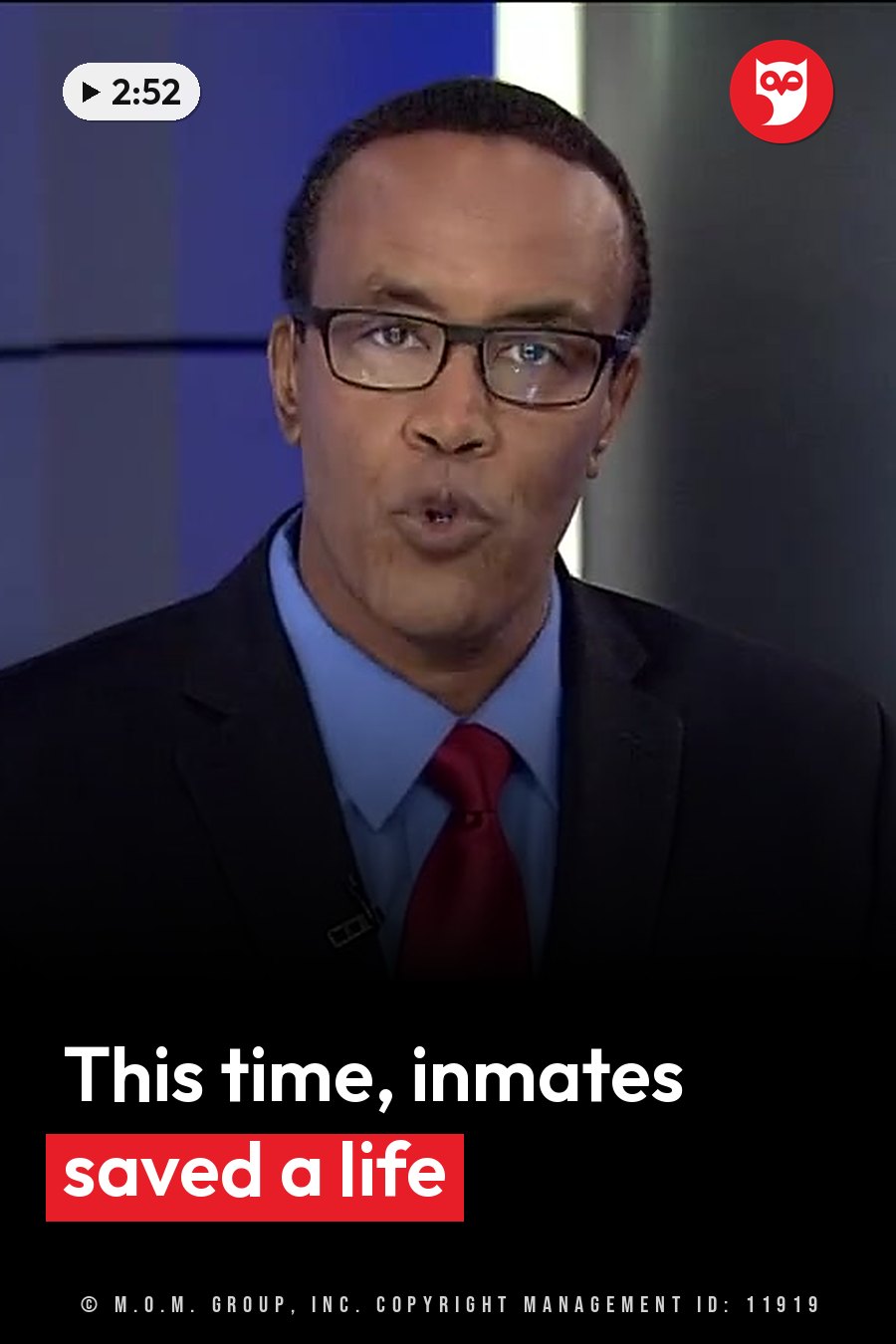A man in glasses, a suit, a blue shirt and a red tie speaks into a microphone on a TV news set. A headline runs in white letters across the lower third.