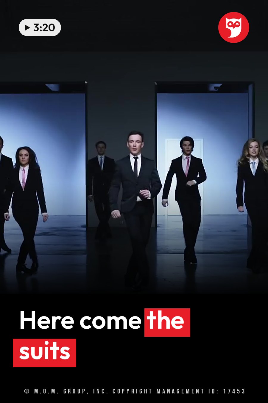 People in suits walk forward through lit doorways in a dim room with a shiny, reflective floor. A headline runs in white letters across the lower third.