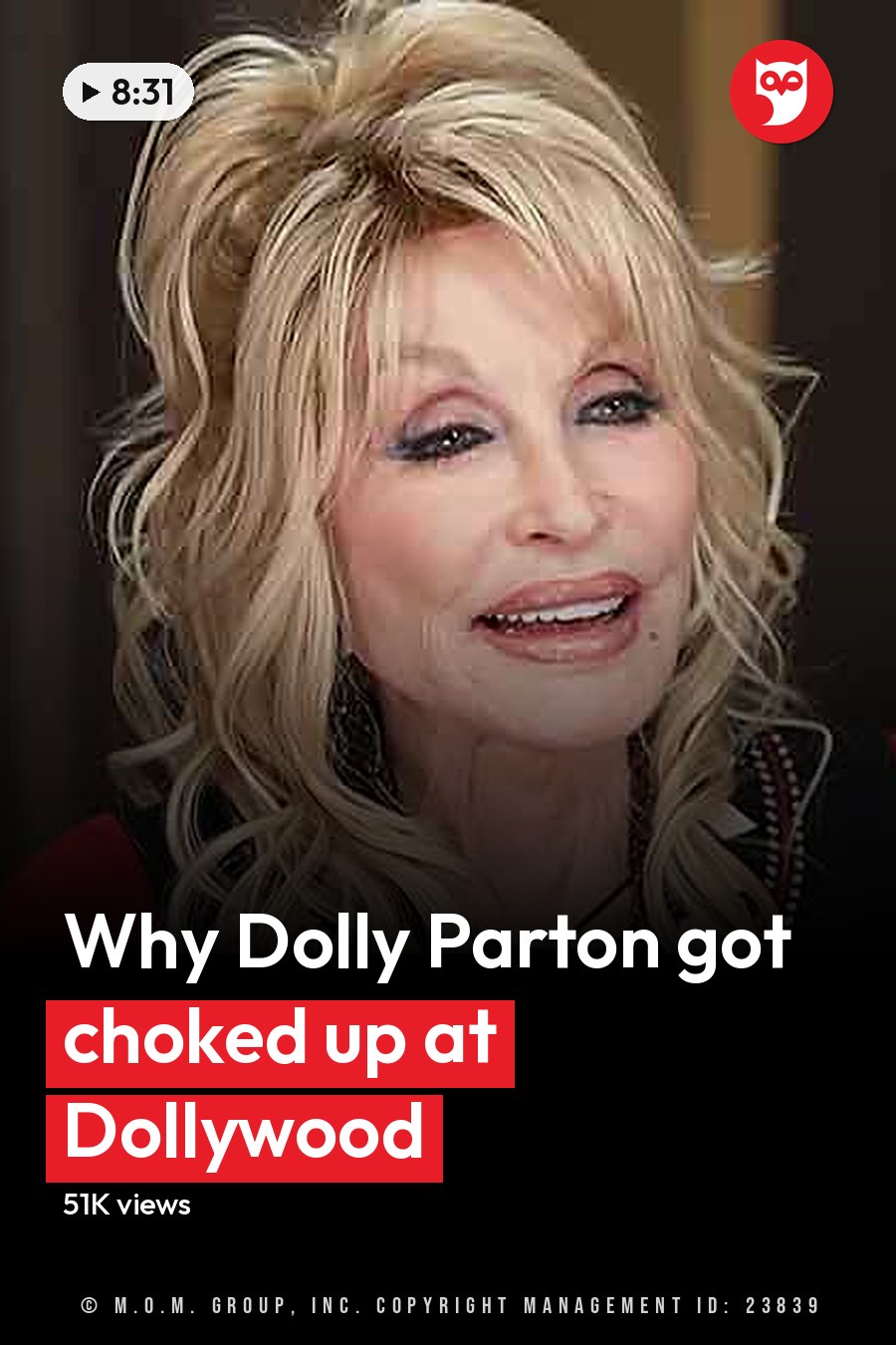 A middle-aged woman in a black top with intricate patterns, paired with a red cardigan or jacket, seated indoors with decorative furniture and a guitar in the background. The headline runs in white letters across the lower third.