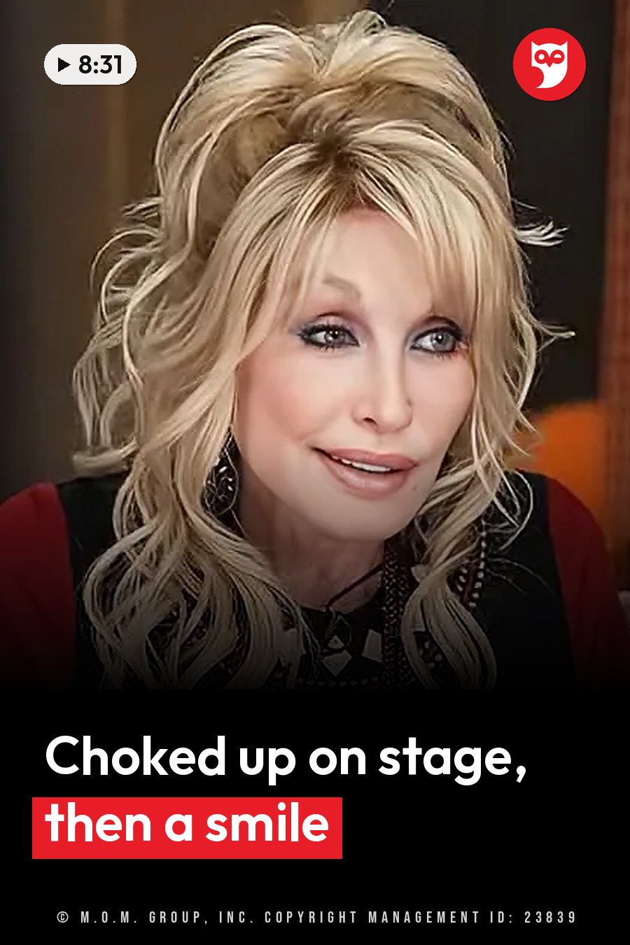 Dolly Parton, her blonde hair styled up, wears earrings and a red-sleeved top and smiles slightly at the camera. A headline runs in white letters across the lower third.