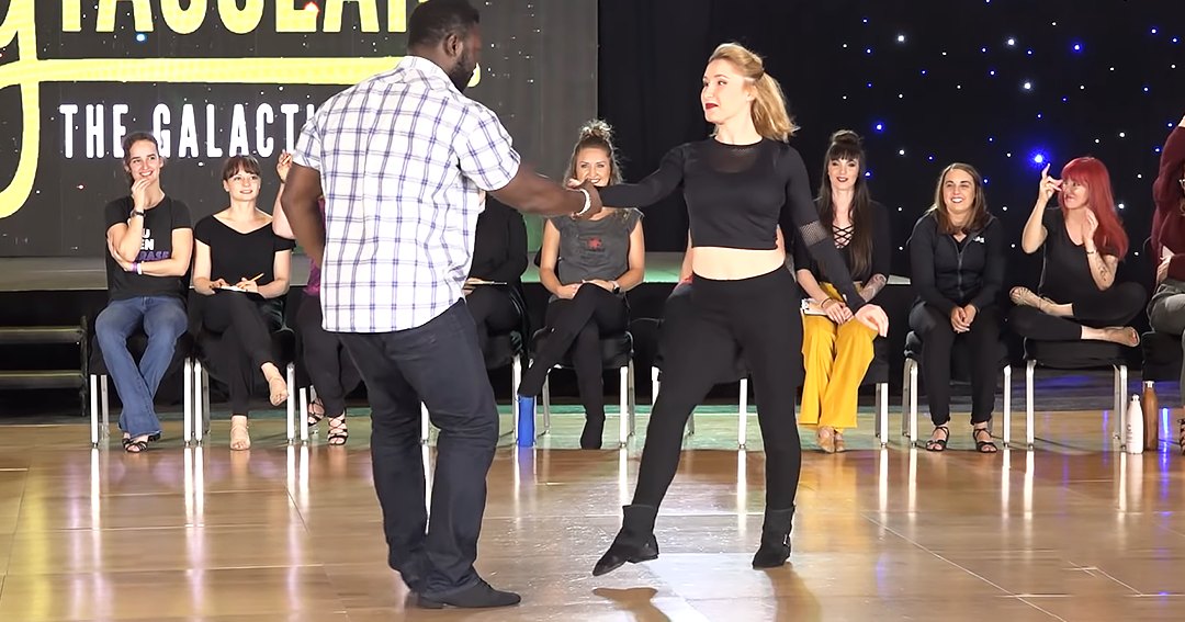 A dance performance at a studio or event space with participants in various settings and attire, including a man leading and a woman dancing.