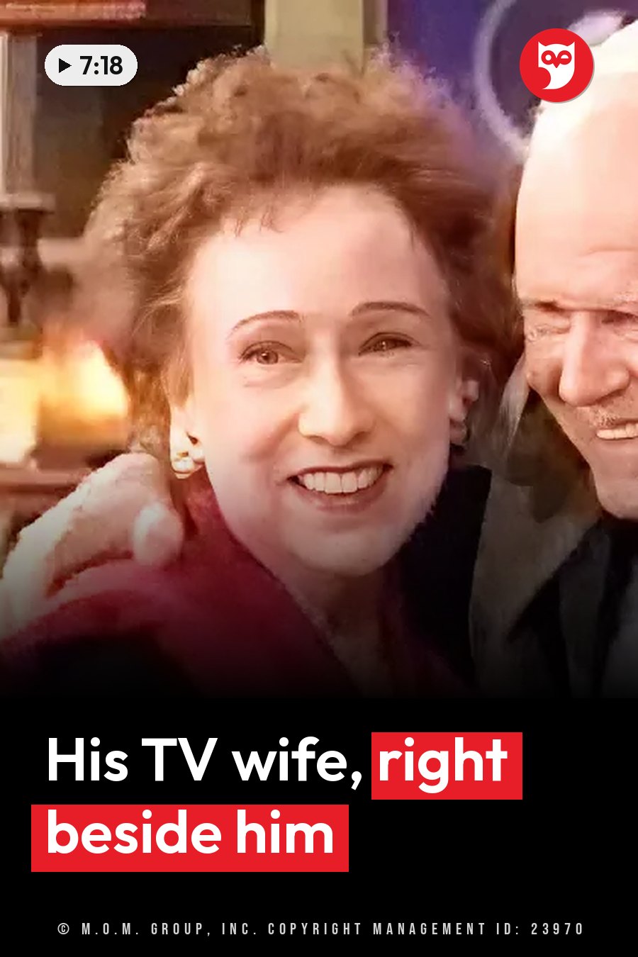 A woman with curly hair smiles while a man puts his arm around her shoulder indoors. A headline runs in white letters across the lower third.