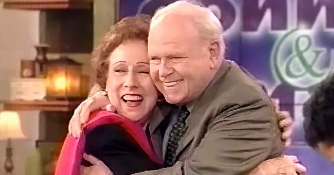 An older adult couple embracing in a cozy indoor setting with natural daylight filtering through an unseen window.