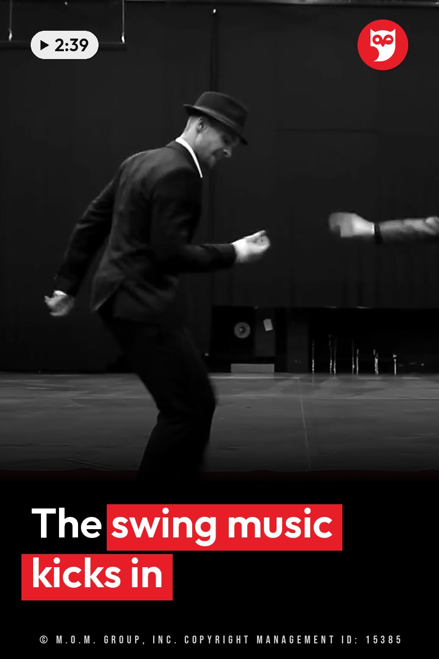 A man in a suit and hat dances on a stage, with a second dancer partly visible beside him. A headline runs in white letters across the lower third.