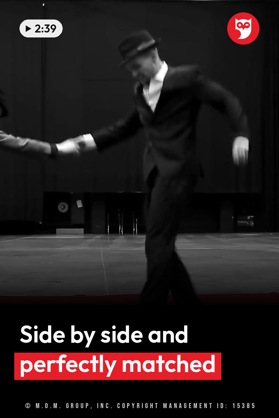 A man in a suit and hat dances with a partner on a stage, arms stretched out, the picture blurred by motion. A headline runs in white letters across the lower third.