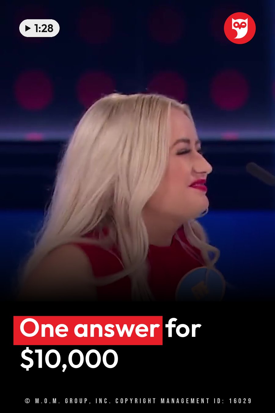 A blonde woman in a red top smiles and looks to her right on a stage lit in blue and pink. A headline runs in white letters across the lower third.