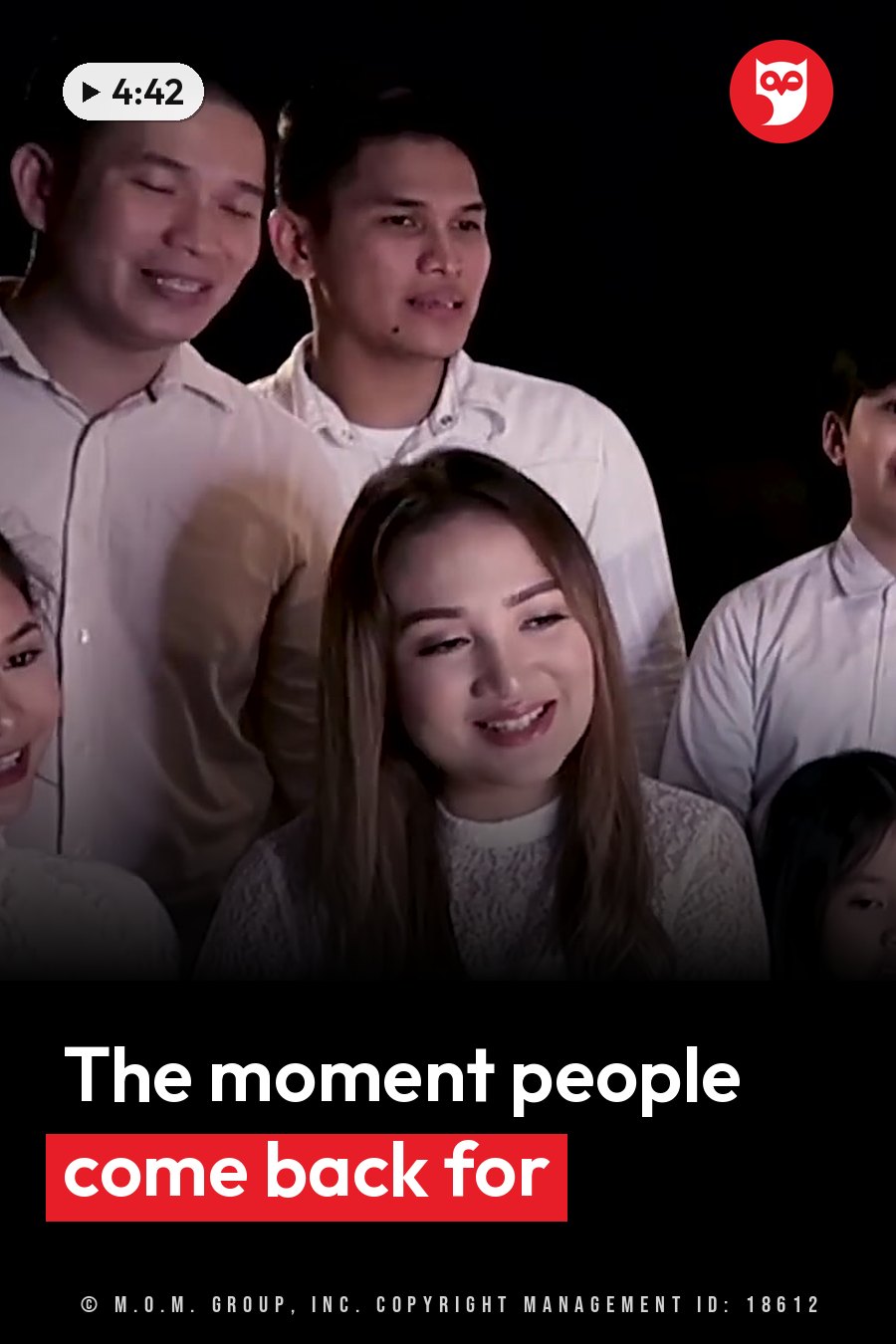 Several people stand together in dim light, smiling and facing forward. A headline runs in white letters across the lower third.