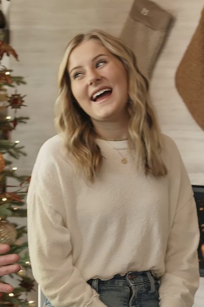 A young couple in front of a decorated Christmas tree, likely at home during winter.