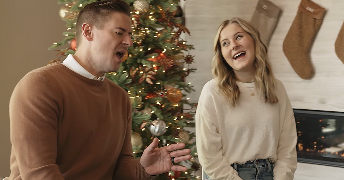 A young couple in front of a decorated Christmas tree, likely at home during winter.