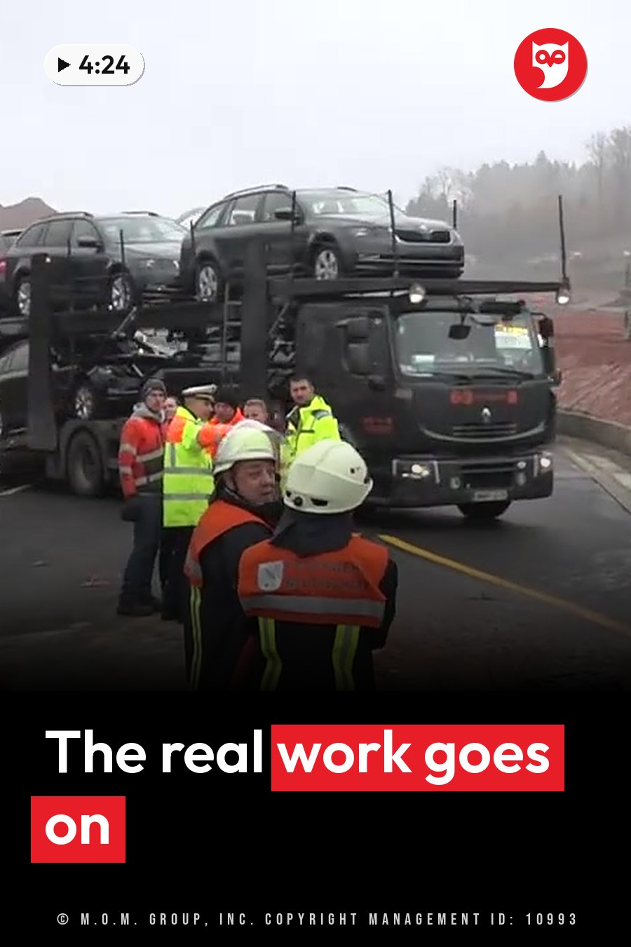 Workers in safety gear stand near a car carrier truck loaded with vehicles on a wet road. A headline runs in white letters across the lower third.