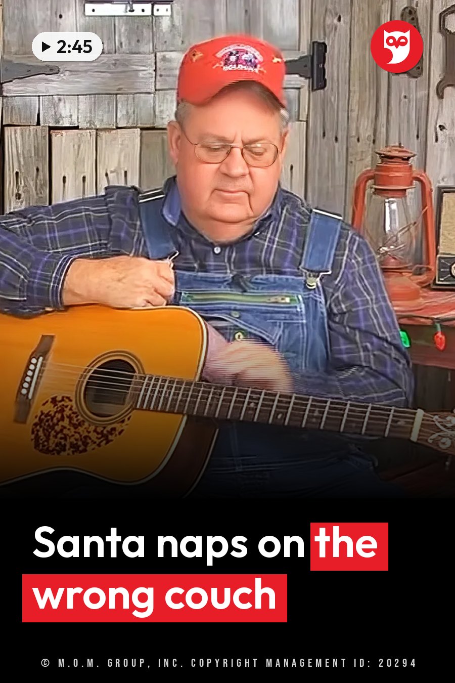 A man in a red cap and overalls plays an acoustic guitar indoors, next to a wooden wall and a lantern. A headline runs in white letters across the lower third.