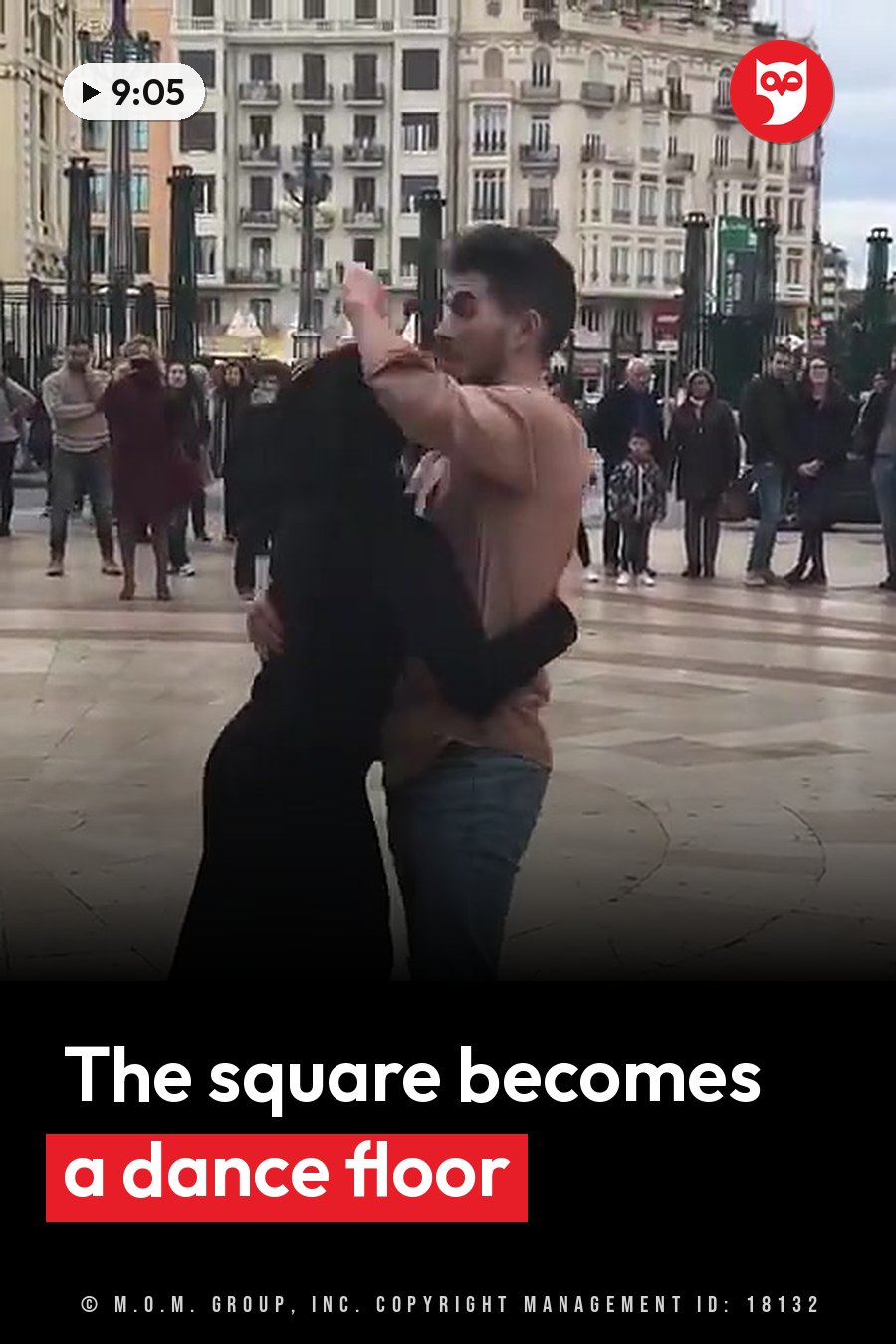 Two people dance closely in a public square while onlookers stand nearby and watch. A headline runs in white letters across the lower third.