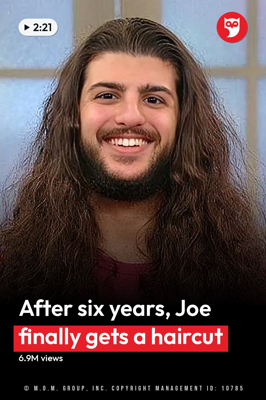 A man with long hair and a beard smiles while wearing a pink shirt indoors near a window. The headline runs in white letters across the lower third.