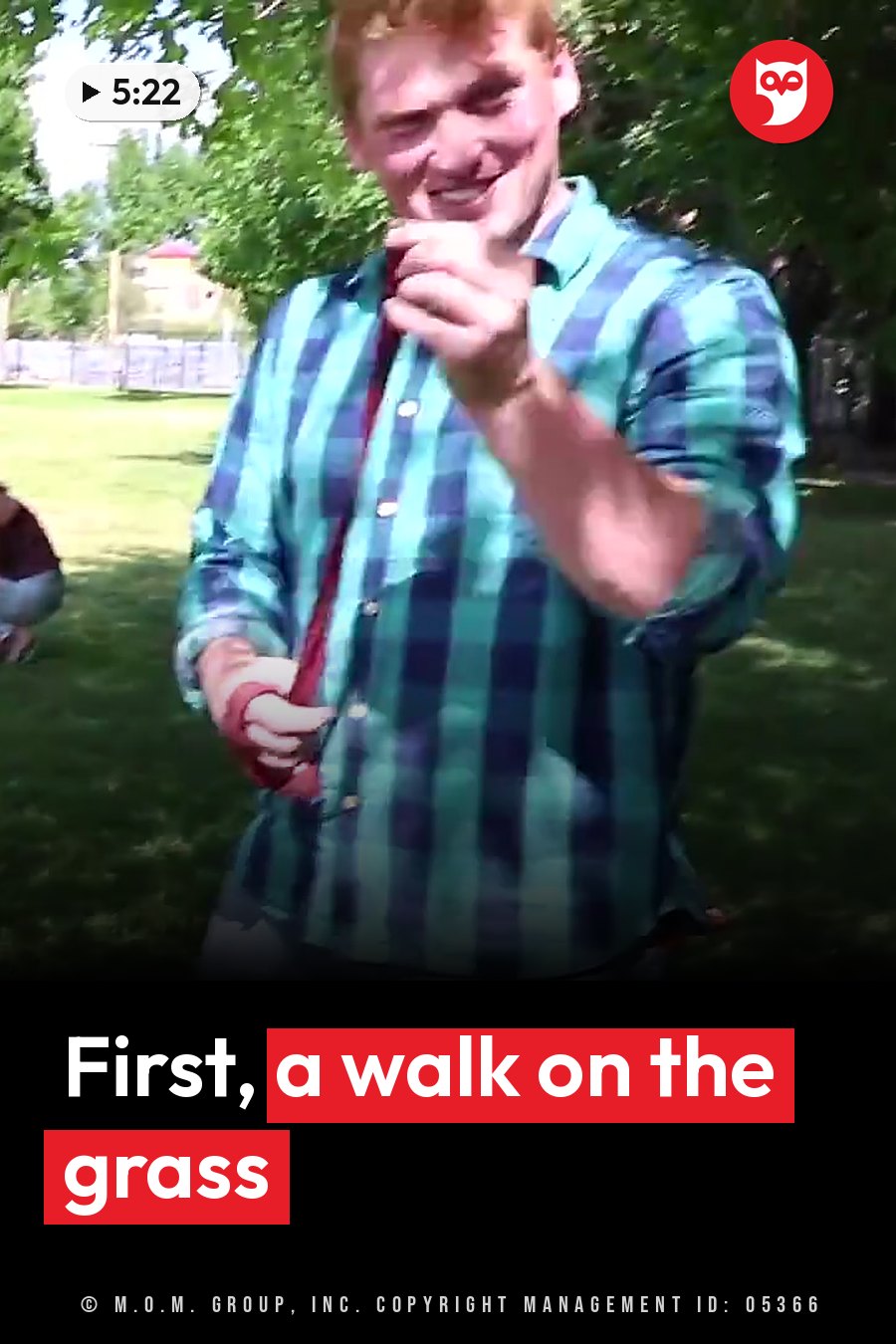 A man in a plaid shirt smiles outdoors on the grass, holding a small object near his mouth. A headline runs in white letters across the lower third.