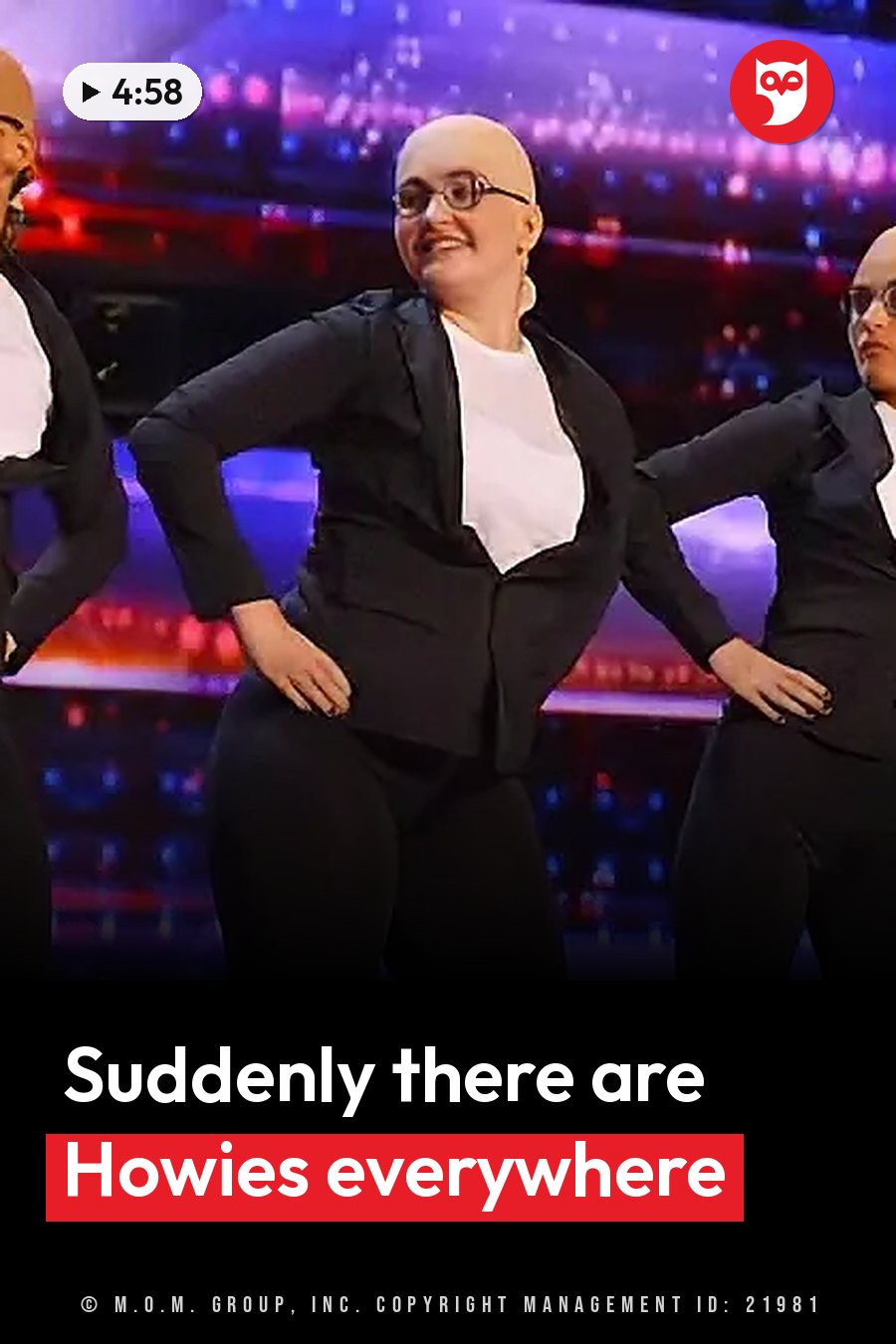 Three people in black suits dance on a stage with colorful lights behind them. A headline runs in white letters across the lower third.