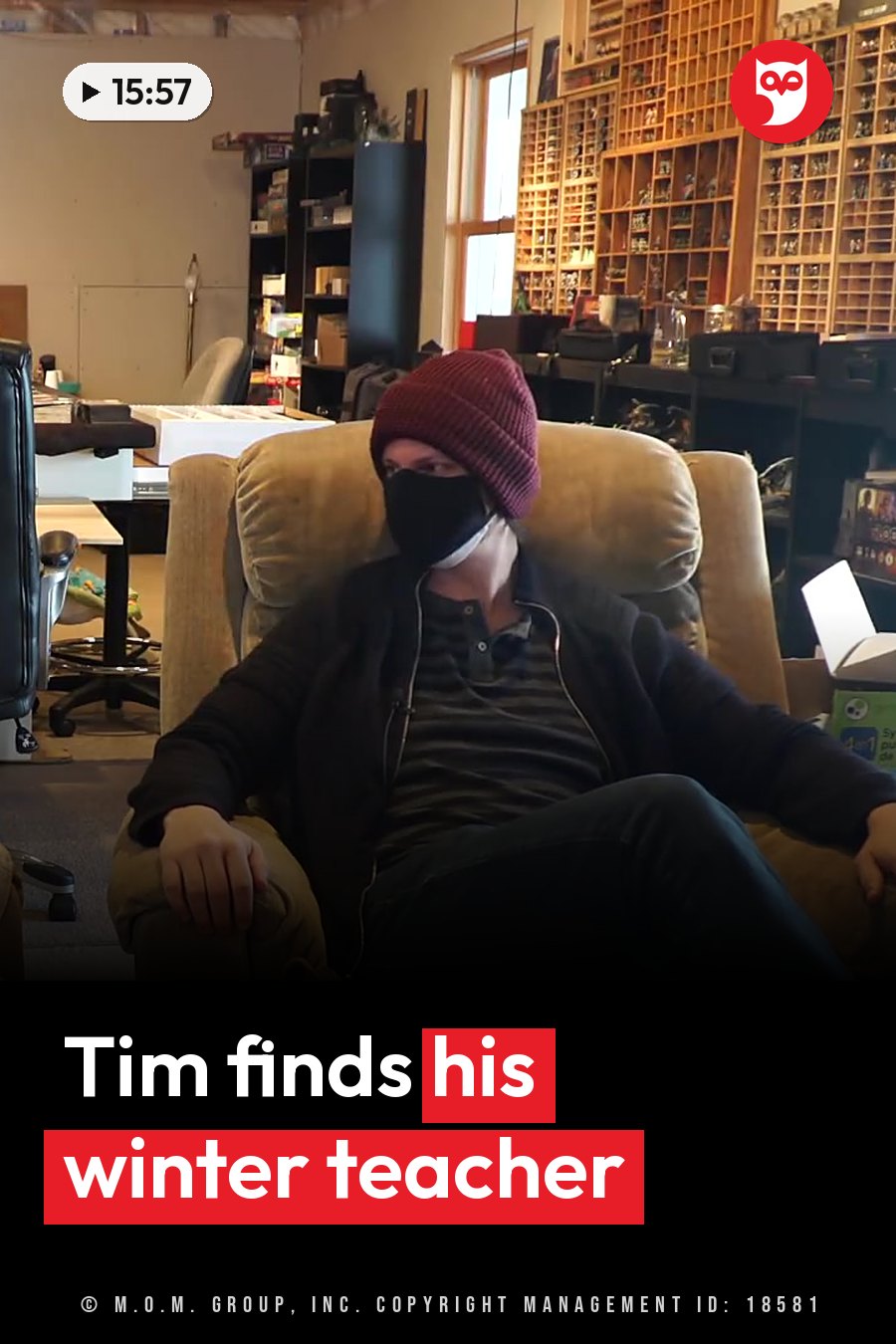 A person in a face mask and beanie sits back in a chair in a room lined with shelves of small items. A headline runs in white letters across the lower third.