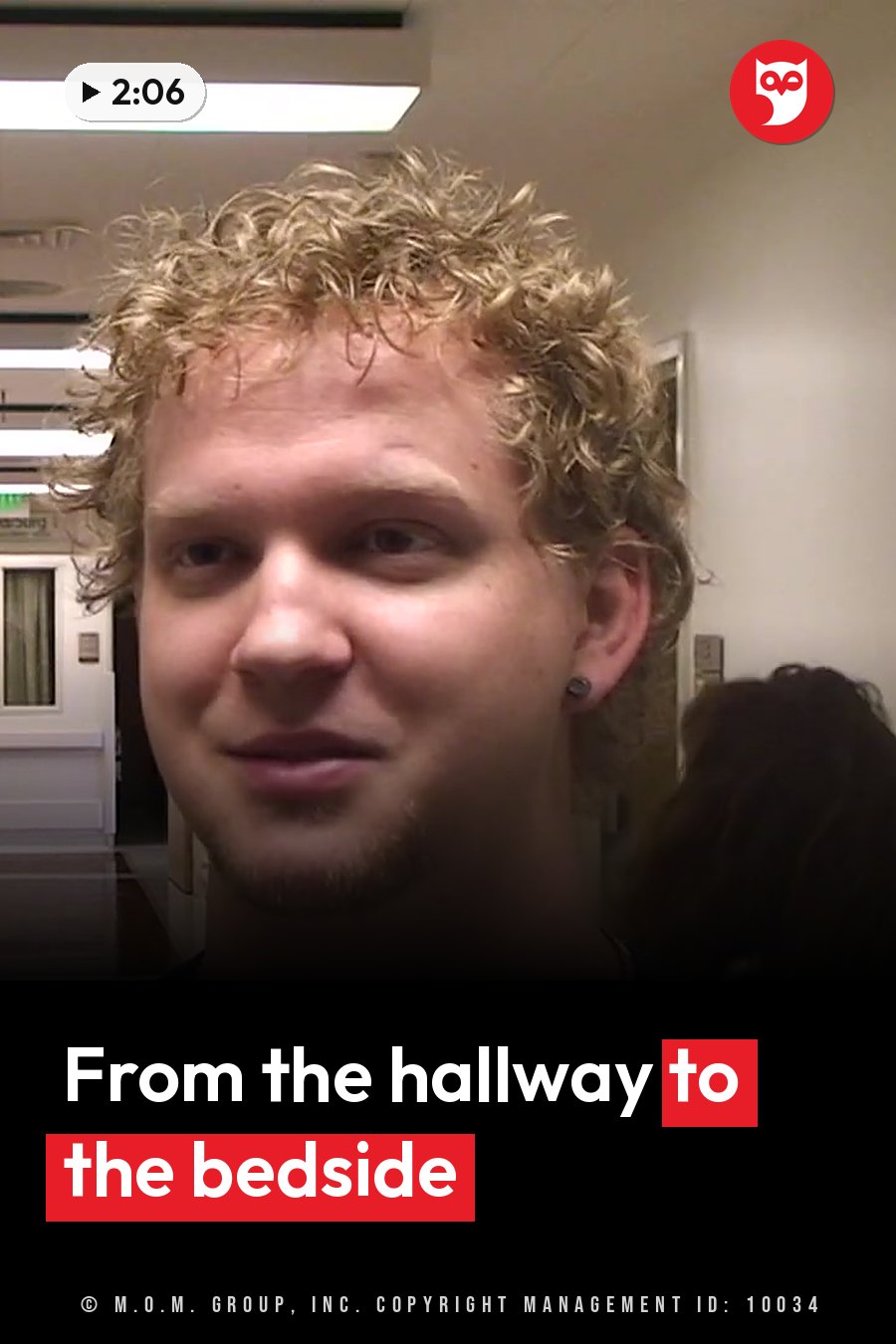 A young man with curly blond hair and an earring looks toward the camera in an indoor room. A headline runs in white letters across the lower third.