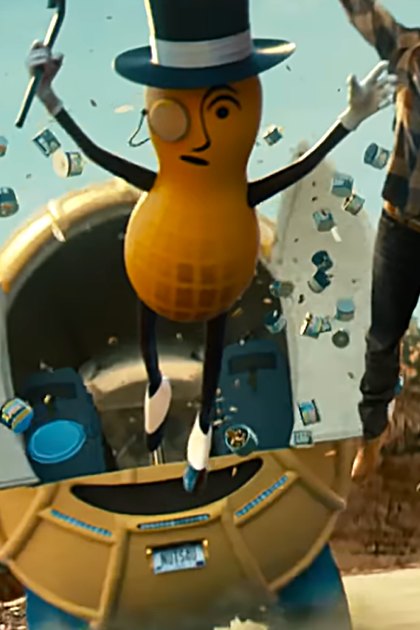 A peanut character in a top hat stands outdoors among scattered Planters Mixed Nuts cans against a desert-like rocky terrain with clear skies.