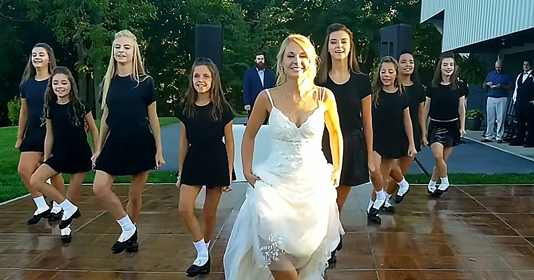 An outdoor wedding reception scene with a bride in a white wedding dress and young adults wearing black dresses, surrounded by greenery and natural light.