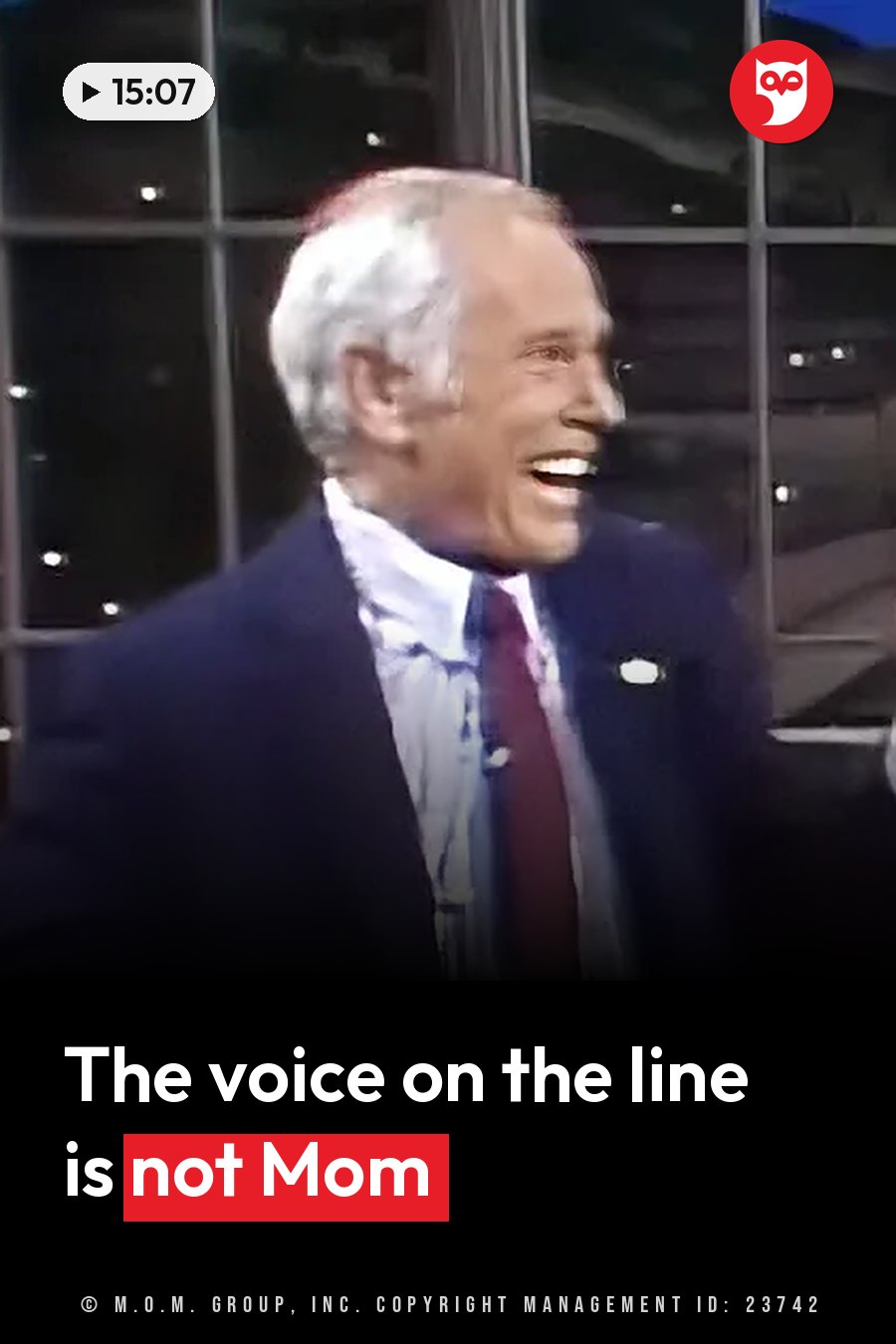An older man with white hair, in a suit and tie, laughs broadly with windows behind him. A headline runs in white letters across the lower third.