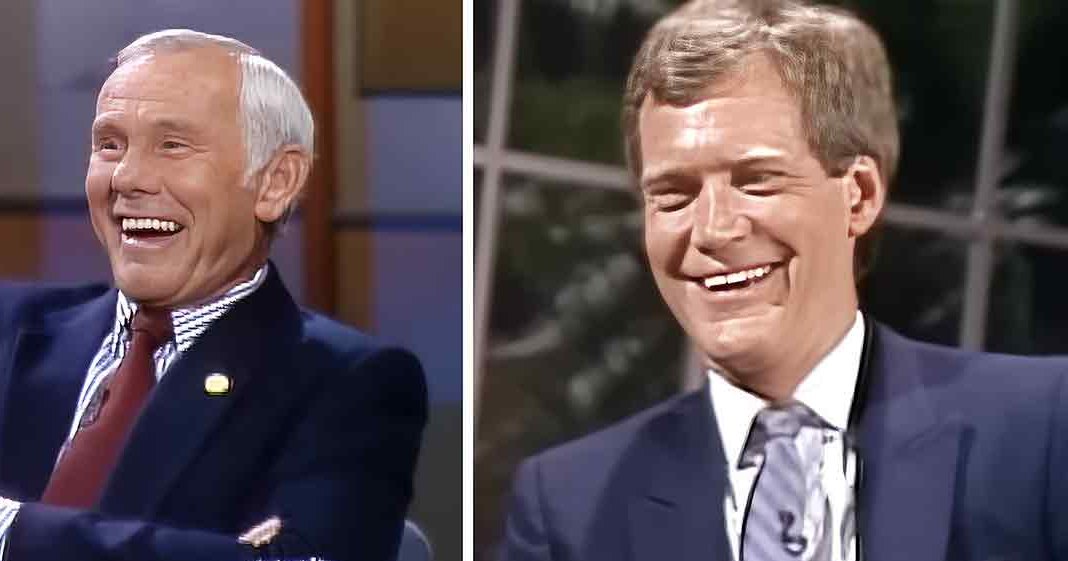 Two adults, an older male and a younger male, wearing formal suits from the mid-20th century, seated in what appears to be a television studio setup with professional lighting.
