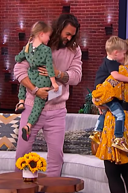 A family scene in a studio setting with adults and children dressed in casual attire.