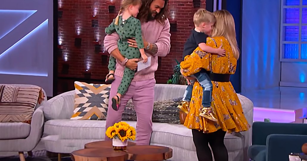 A family scene in a studio setting with adults and children dressed in casual attire.