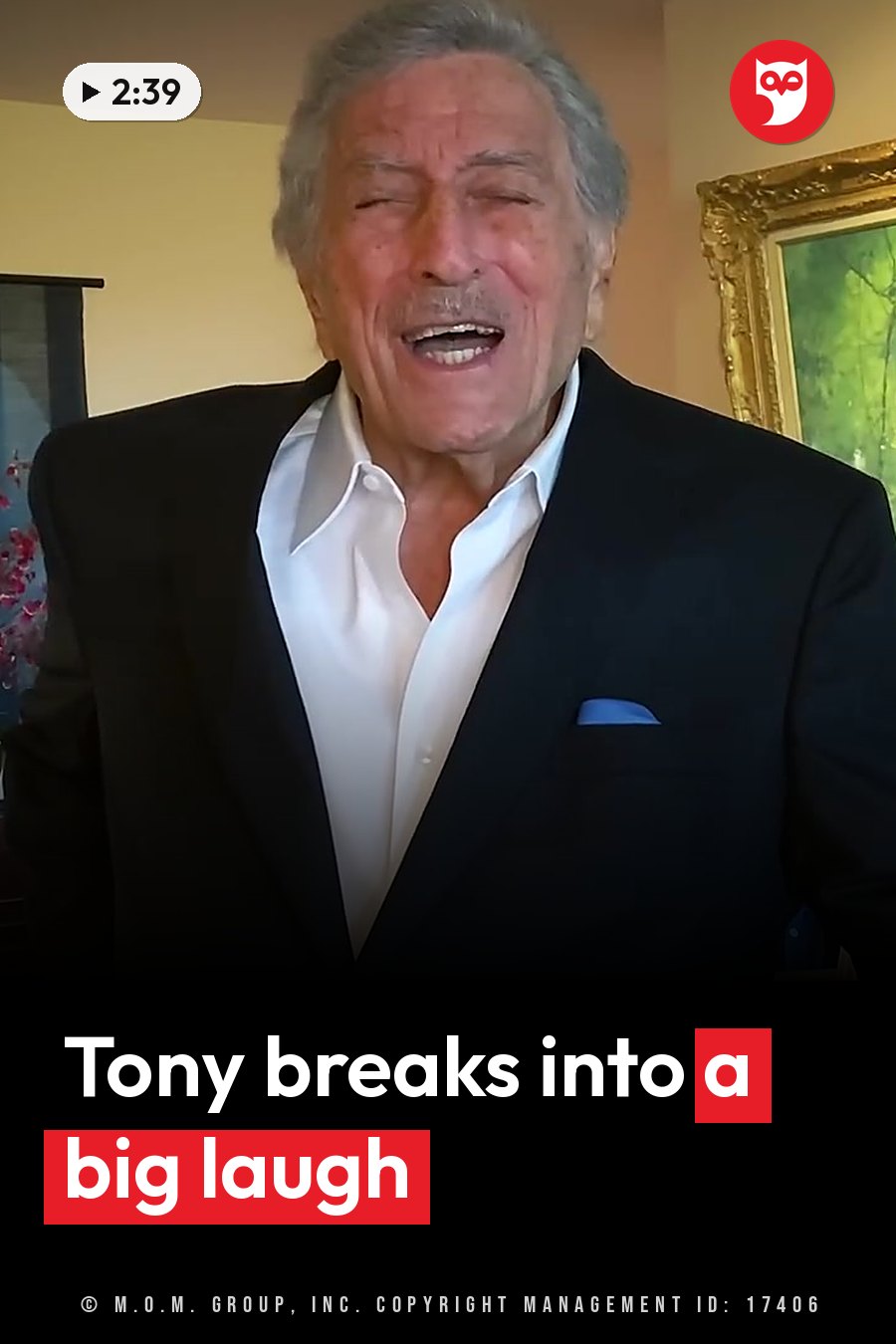 An older man with gray hair laughs broadly, wearing a black suit jacket over a white shirt. A headline runs in white letters across the lower third.