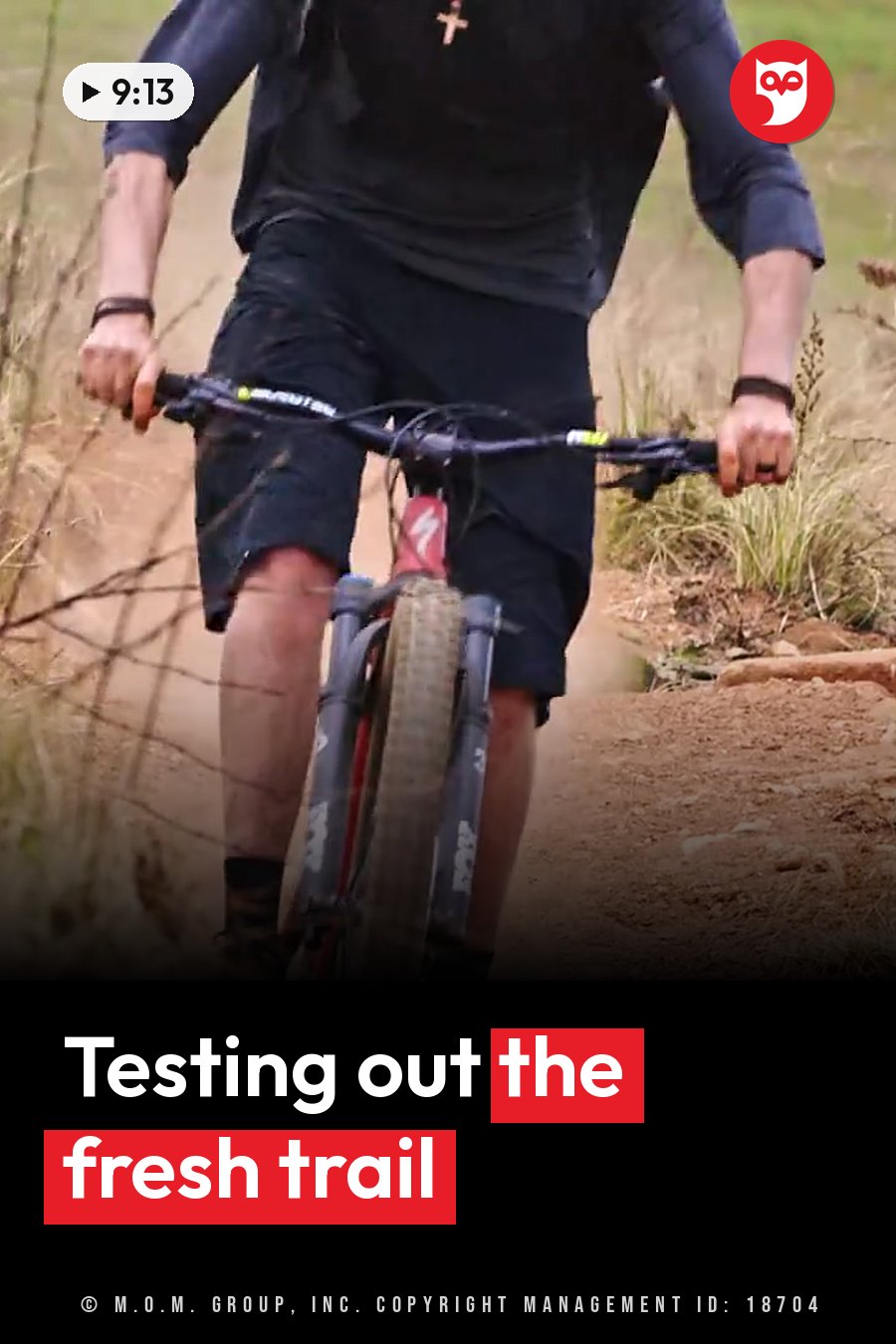 A person rides a mountain bike along a dirt trail through grassy ground. A headline runs in white letters across the lower third.
