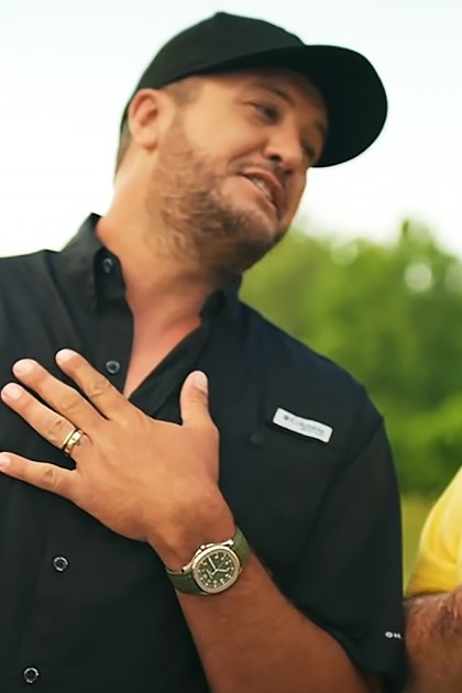 Middle-aged men in a park, one wearing a black button-up shirt with 'Tennessee' branding and the other in a yellow polo shirt holding what appears to be a fishing rod.