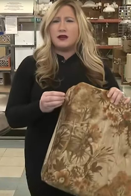 A woman in an indoor thrift shop, wearing a black polo-style top with long sleeves and high neckline.