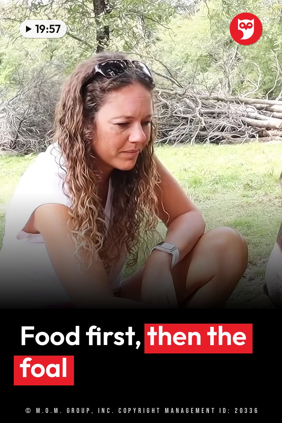 A woman with curly hair, a white shirt and a watch sits on the grass, sunglasses pushed up on her head. A headline runs in white letters across the lower third.