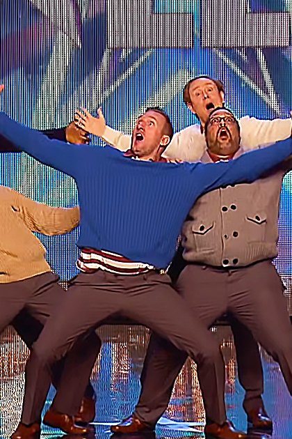 Group performing on stage with a cityscape backdrop at 'Britain's Got Talent' event.