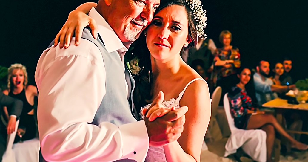 A bride and her father dancing at an outdoor wedding reception during evening. The bride wears a white strapless wedding dress with a floral crown, while the father is in a light-colored suit jacket.