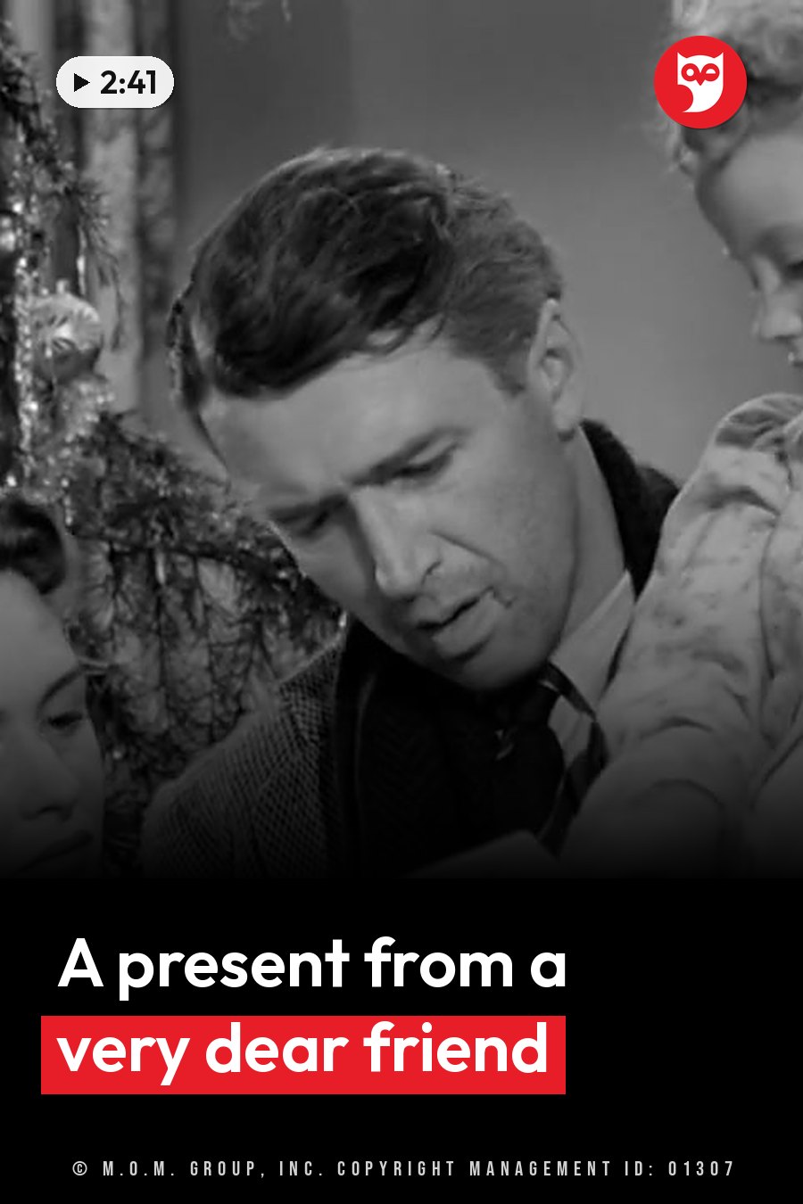 A man looks down while holding a child, with a woman partly visible beside him near a decorated Christmas tree. A headline runs in white letters across the lower third.